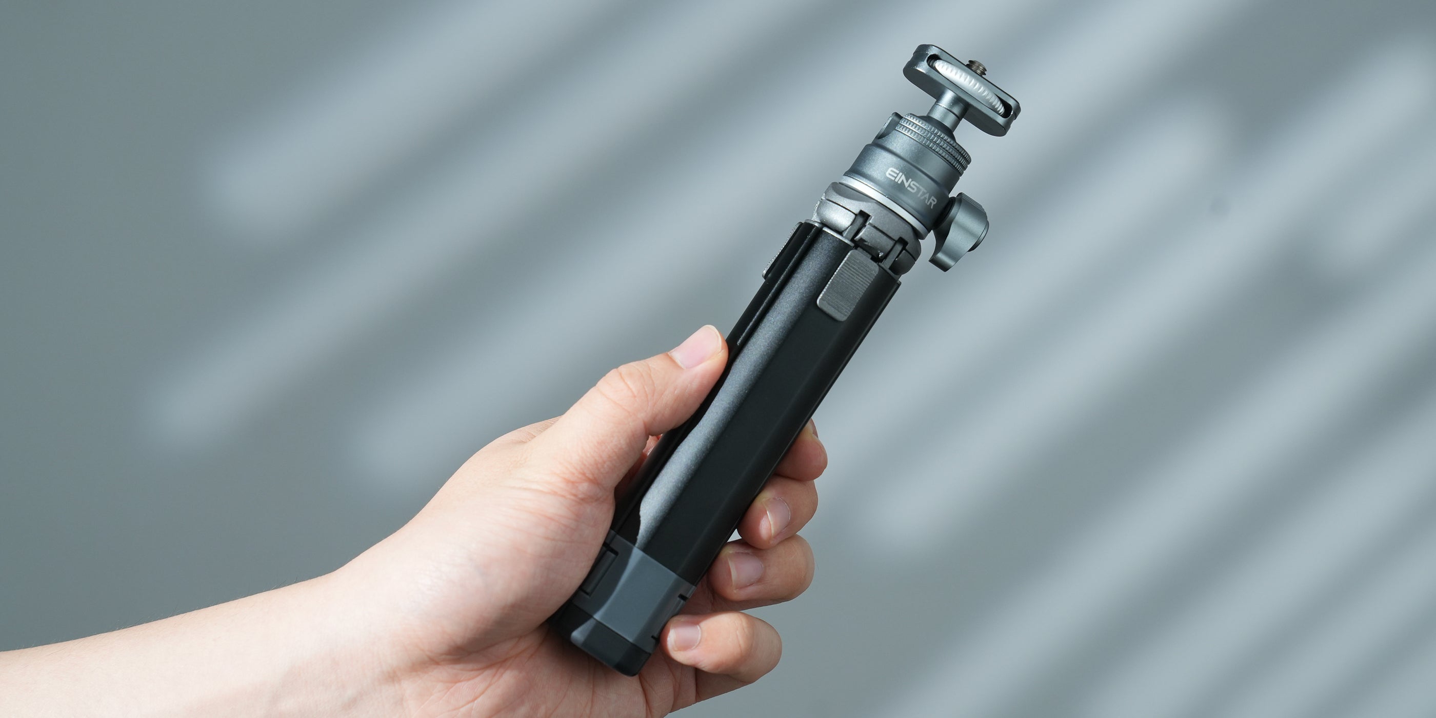 Hand holding a compact and lightweight EINSTAR tripod, showcasing its portability with a folded length of 19cm and a weight of 0.25kg, making it easy to carry and handle.