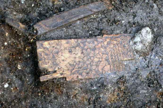 Preserved wooden artifact with intricate carvings found in an archaeological dig.